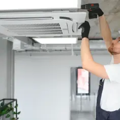 Instalator klimatyzacji montuje jednostkę sufitową w biurze.